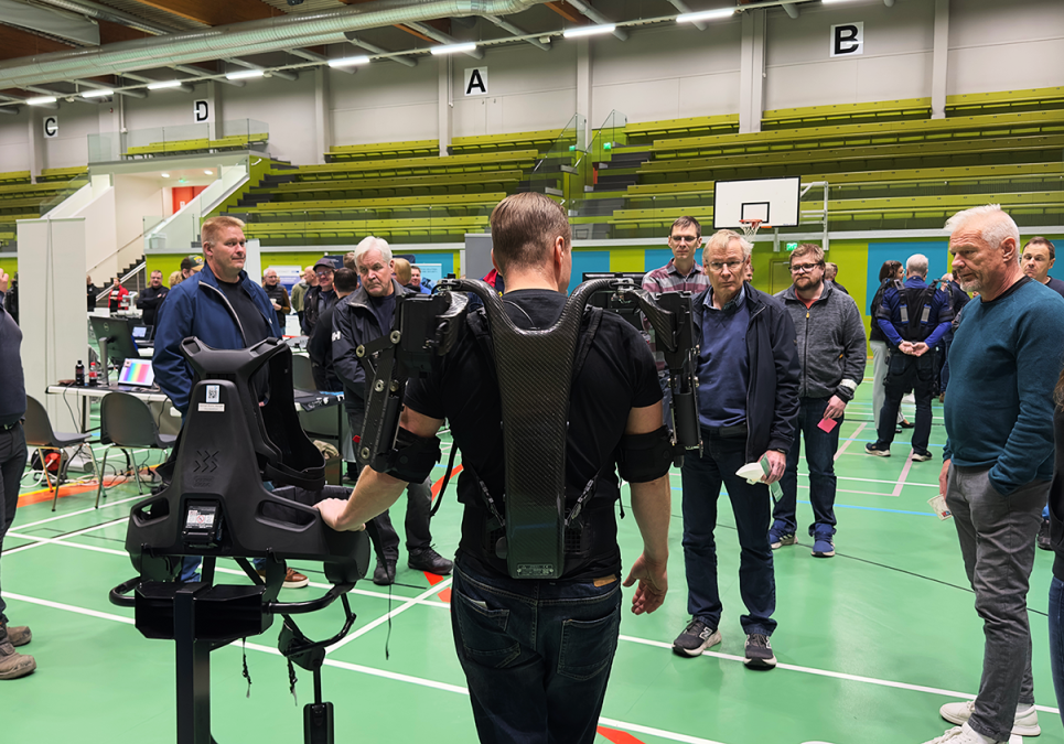 Man dressed in exoskeleton showcasing it to company representatives