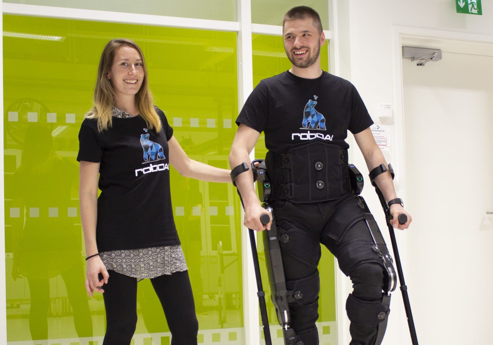 The picture shows a woman and a man using an exoskeleton walking robot.