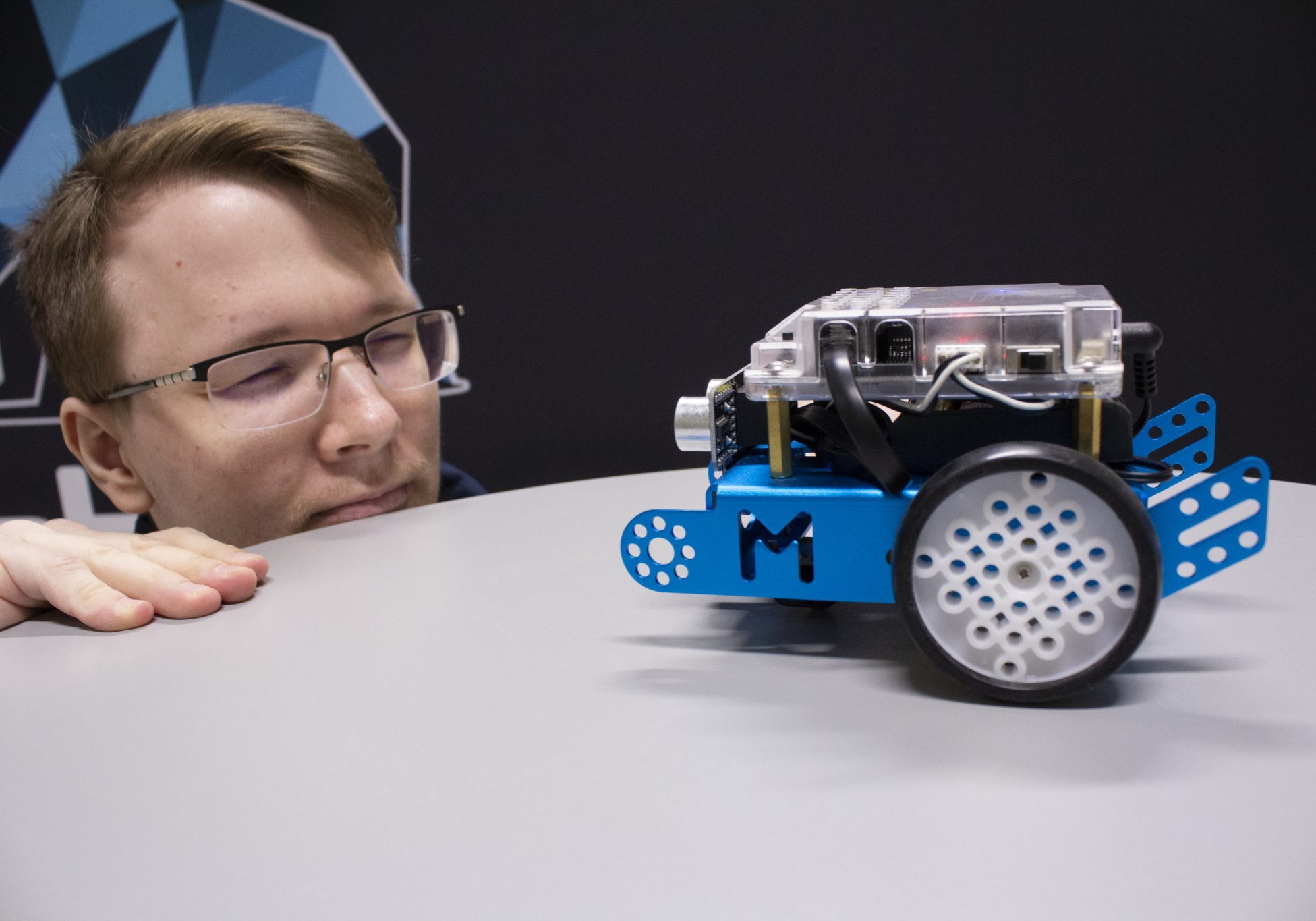 Closeup of student and a small robot. 