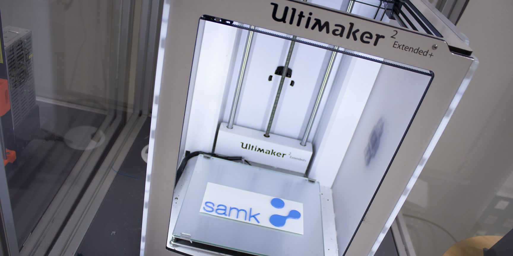 Kuvassa 3D-tulostin ja sen lisällä tulostettu SAMKin logo.