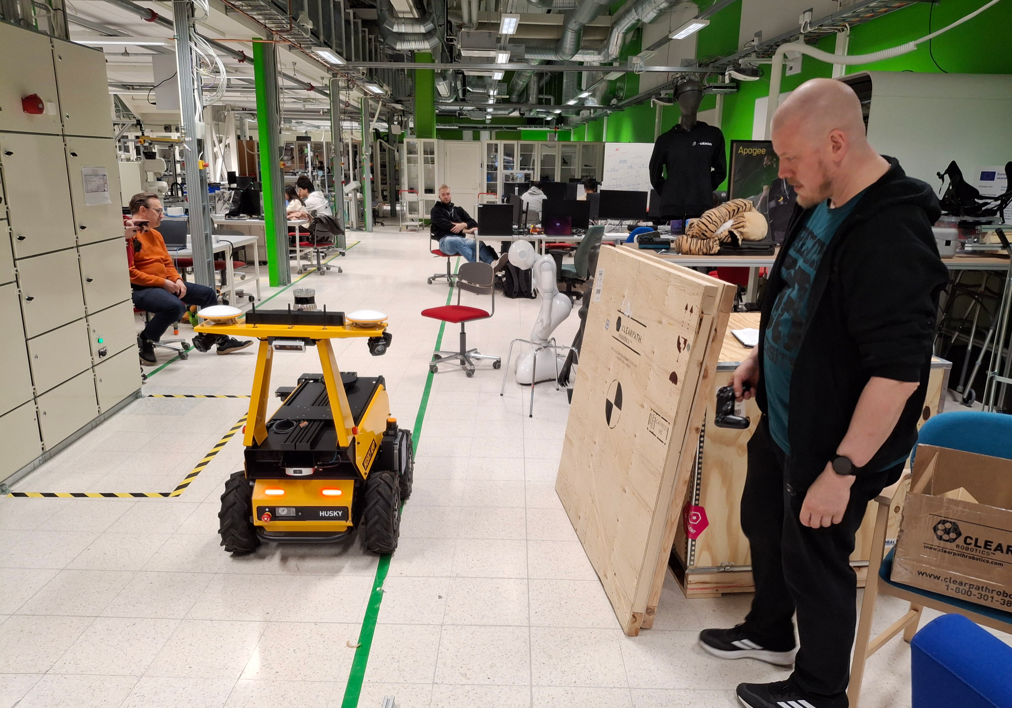 A man staring at a yellow four wheeled robot in a laboratory setting.