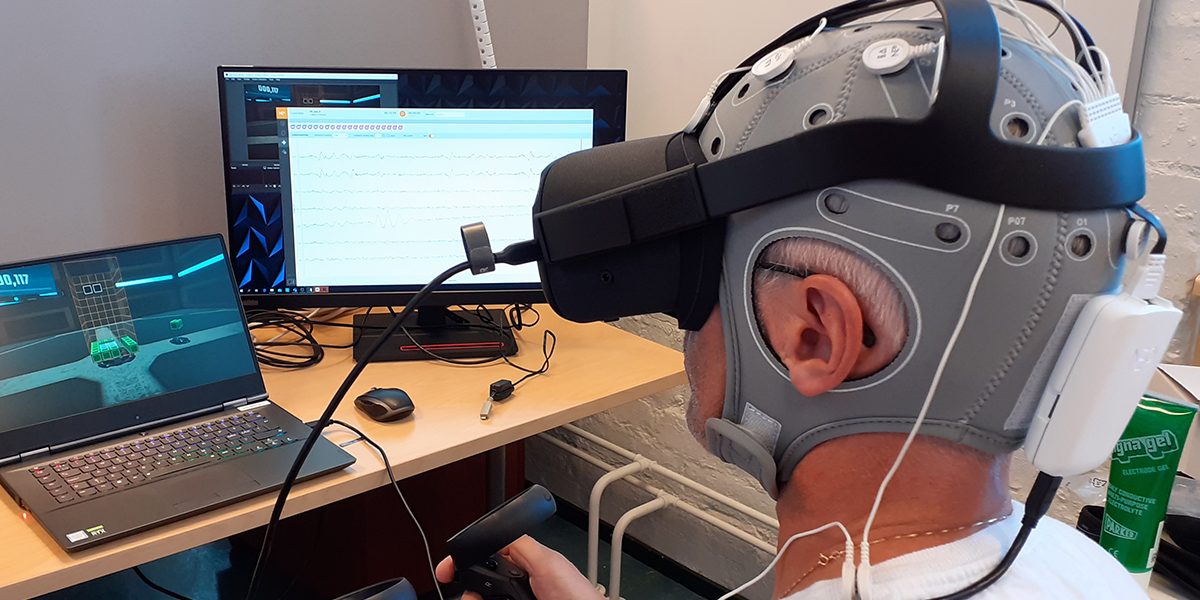 Pääkuva Miehellä päässä EEG-pipo ja VR-lasit.