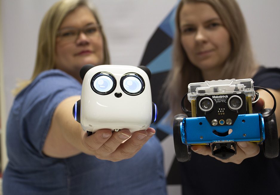 Mirka Leino ja Janika Tommiska pitävät käsissään lapsille tarkoitettuja ohjelmoitavia robotteja.